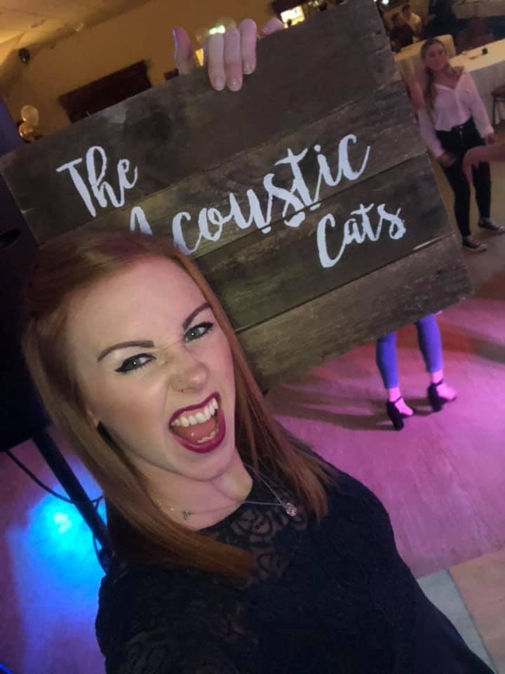 Singer holding The Acoustic Cats sign